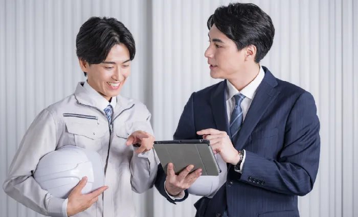 タブレットを手に打ち合わせをする営業担当者と職人