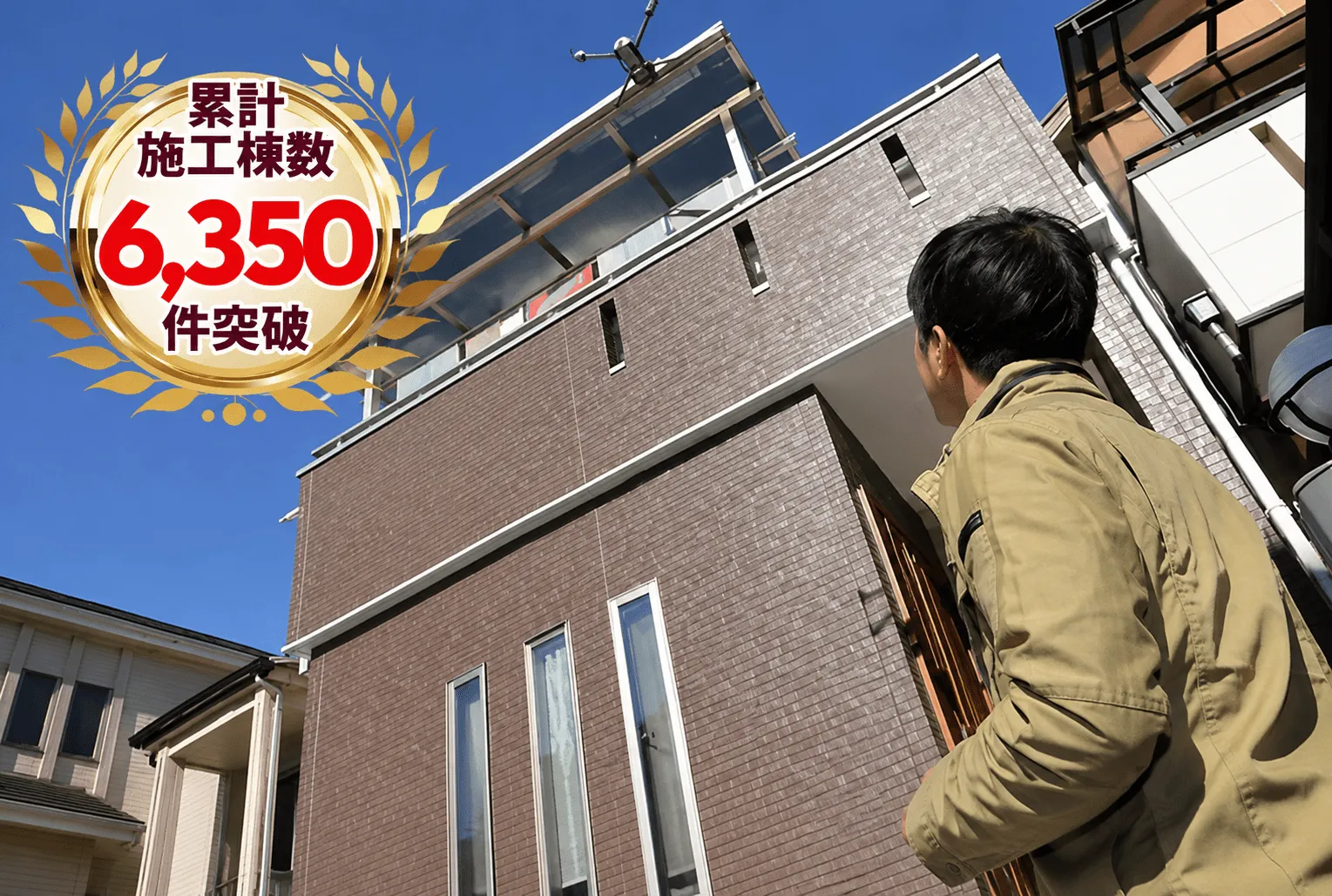 住宅を見上げるスタッフと累計施工棟数6,350件突破のバッジ
